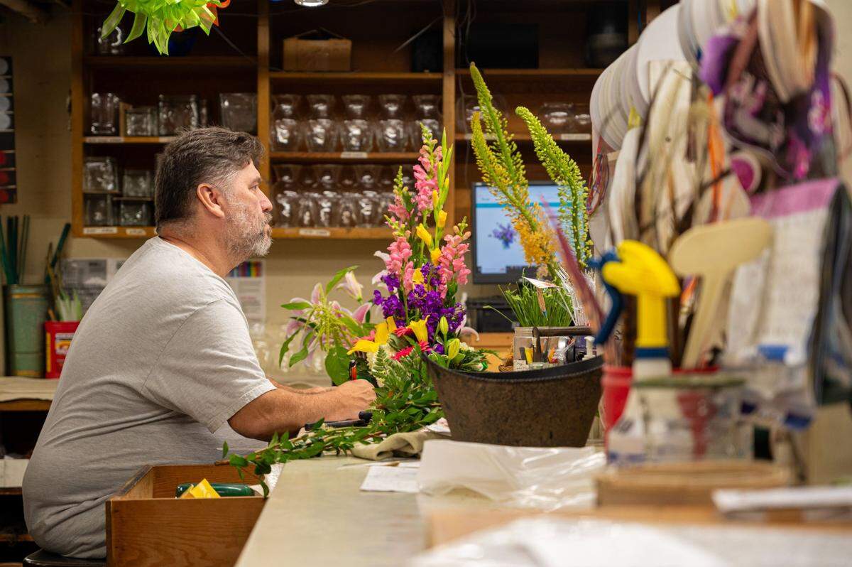Floral designer Raymond Prothero checks his finished arrangement at Relles Florist in Sacramento on Tuesday.