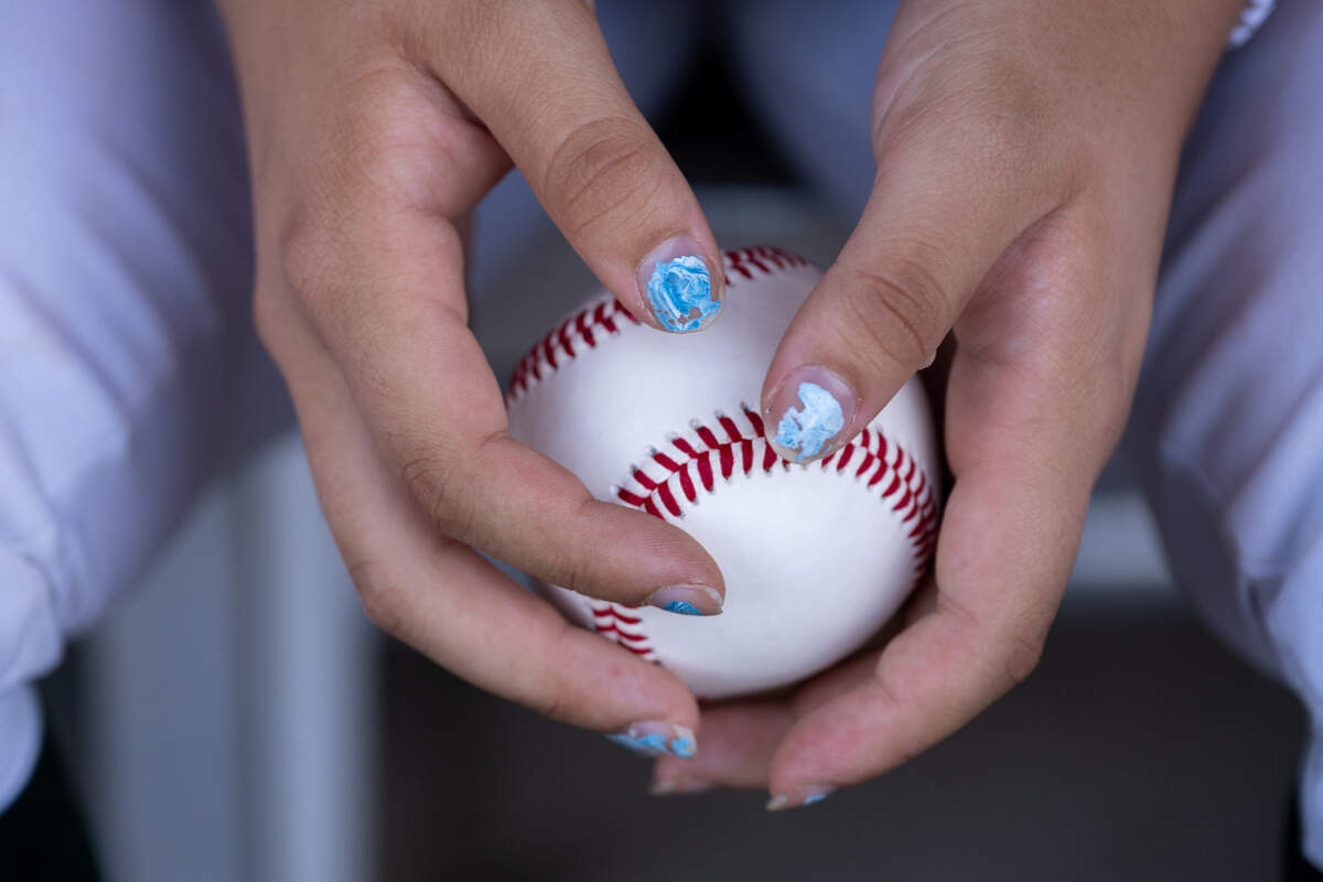 The Kennedy Cougars’ Laney Fukuoka wears blue fingernail polish as she holds a baseball before a game against the Antelope Titans on Monday. Fukuoka pitches and plays first base on the varsity baseball team.