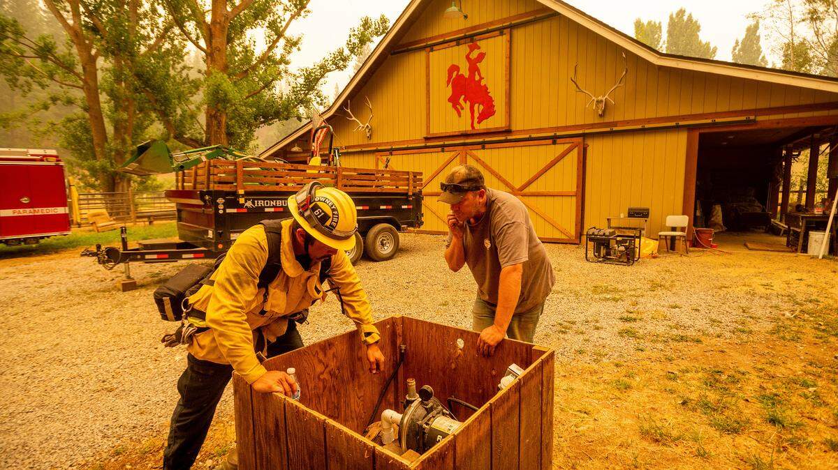 Jesse Ackley and firefighter Sergio Zavala examine a water pump while preparing for the Dixie Fire’s approach in Plumas County, Calif., Sunday, July 25, 2021. Officials expanded evacuation orders earlier in the day. (AP Photo/Noah Berger)
