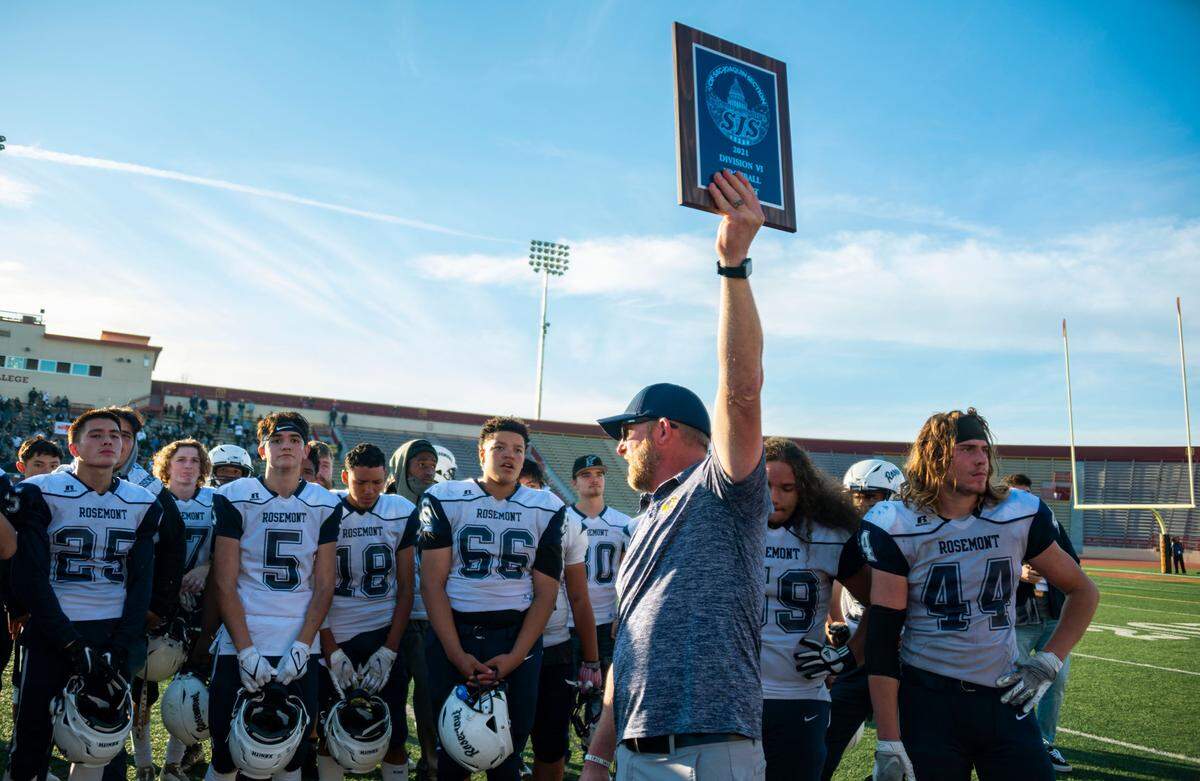 Rosemont coach Rick Wanlin shows the CIF Sac-Joaquin Section Division VI finalist plaque to the crowd while congratulating his team on its season after coming up short against the Argonaut Mustangs in the championship game on Saturday at Hughes Stadium in Sacramento. At right stands Walin’s son Adam (44), a senior tight end and linebacker for the Wolverines.