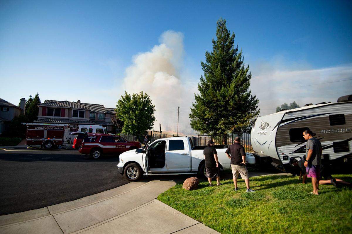 Residents of the Blue Oaks neighborhood in Roseville work to evacuate as members of the Roseville Fire Department and Cal Fire work a grass fire burning in the fields behind their home, Monday, Aug. 10, 2020.