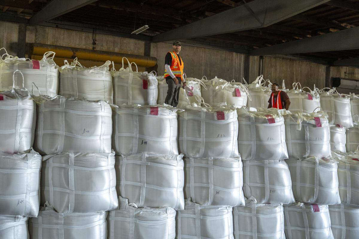 Longshoremen stand atop rice bags inside a rice shed at the Port of West Sacramento on Thursday, July 31, 2025.