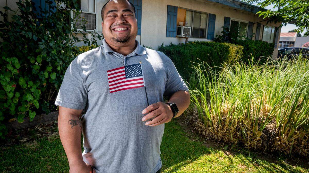 Phorn Tem, who became a citizen in June, holds a U.S. flag as he stands outside his home in Sacramento on Wednesday, July 1, 2020. Tem was deported in 2018 based on a decades-old conviction for possession of marijuana that was later vacated. He is the first Cambodian deportee to return to the U.S. to become a citizen.