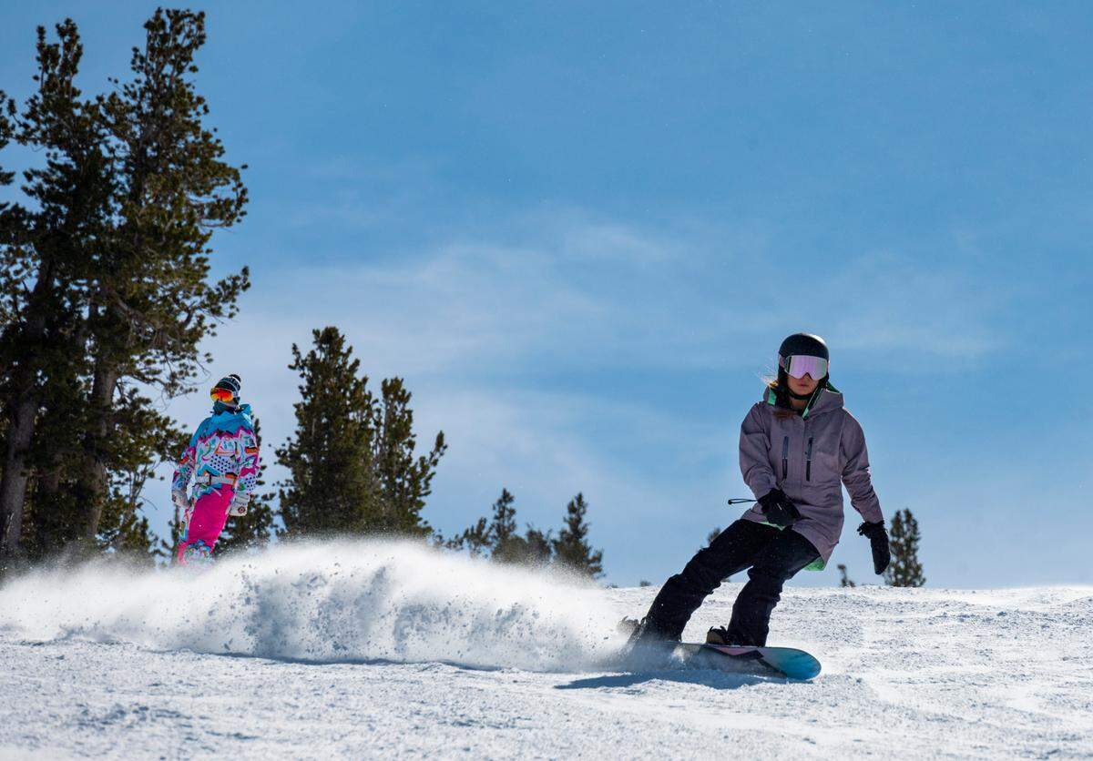 Powder flies into the air as snowboarders cruise down a run at Heavenly Mountain Resort on Friday, Feb. 10, 2023.