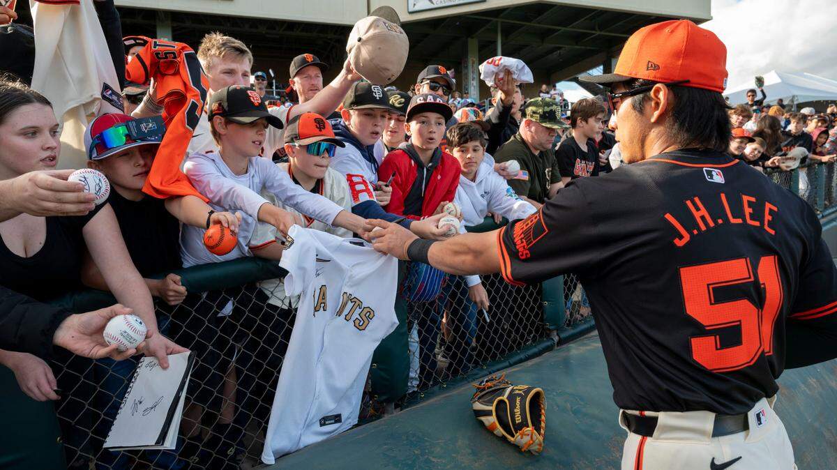 San Francisco Giants center fielder Jung-Hoo Lee, a South Korean player who will play his first major league season after signing a six-year, $113 million contract with the Giants in December, signs autographs for fans at Sutter Health Park before a Sunday exhibition game against the Sacramento River Cats.