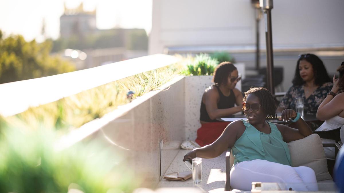 Flo Cofer, of Sacramento, settles in at an outdoor table with friends and Sacramento Sister Circle members before the sun sets at the Clayton Club Rooftop Lounge on Wednesday, Aug. 3, 2022, at the Hyatt Centric Downtown Sacramento.