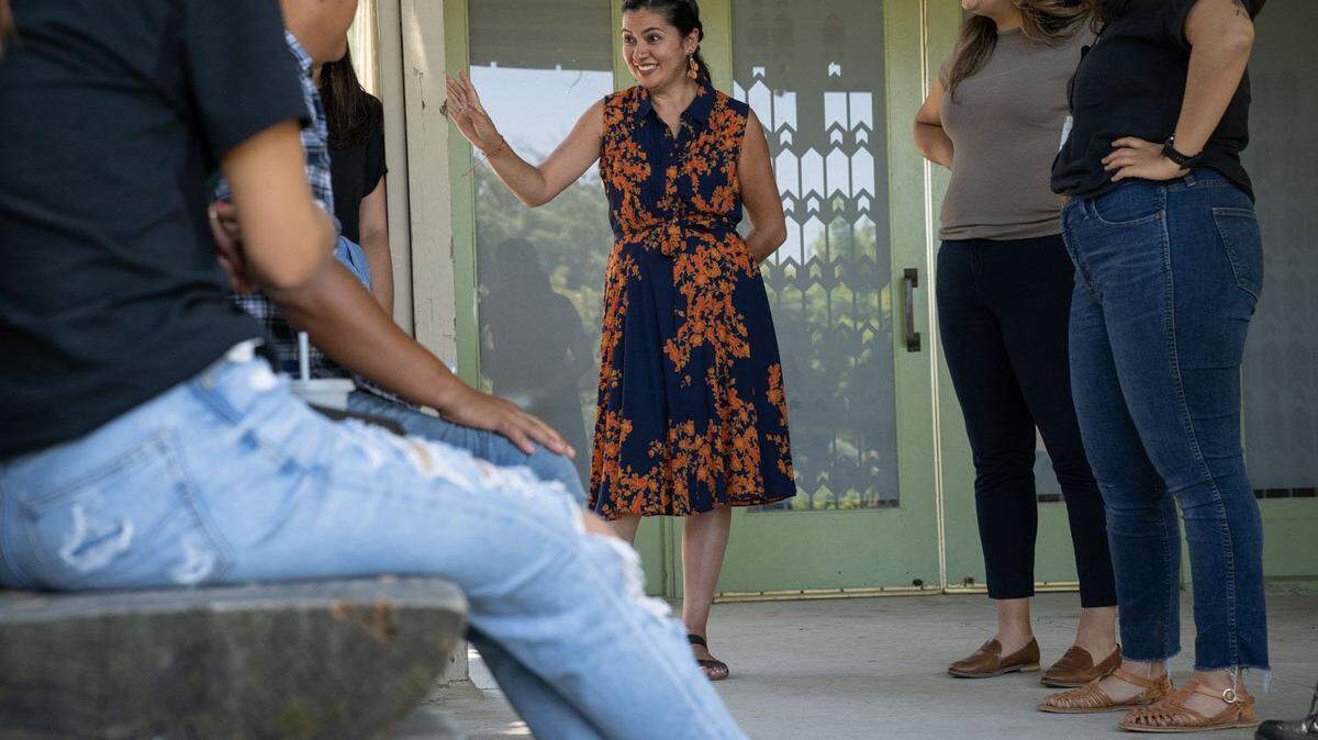 Gabby Trejo, executive director of multi-congregation religious organization Sacramento ACT, talks on Friday, June 16, 2023, with members of the group of migrants, left, that were flown to Sacramento from El Paso, Texas, on two flights by a Florida contractor.