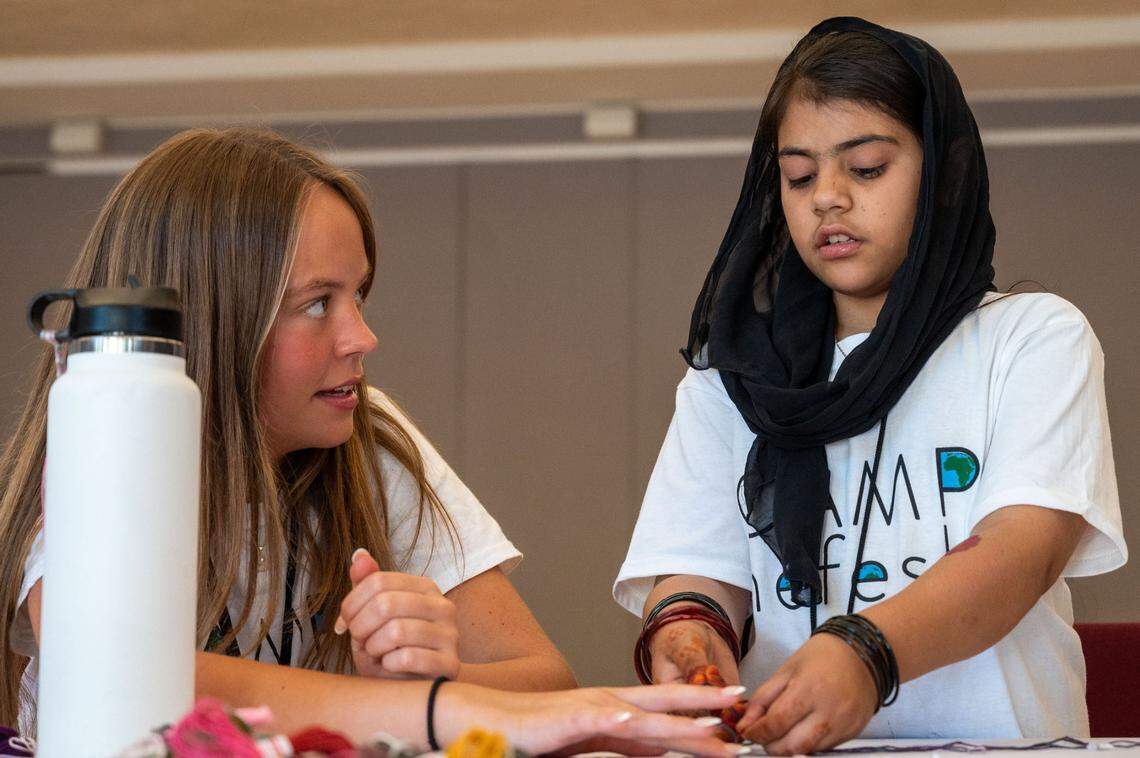 Camp counselor Liberty Daily, 17, helps Zenat Rahmani, 10 braid a friendship bracelet at Camp Nefesh in Sacramento on June 19, 2024.