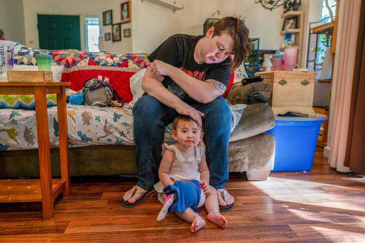 Transportation Security Officer Mary Becker, 31, strokes the head of her 14-month-old daughter, Alice, in their living room in Roseville on Thursday. “We barely survived and floated through March,” she said, worrying about providing for her daughter, paying rent and escalating gas prices.