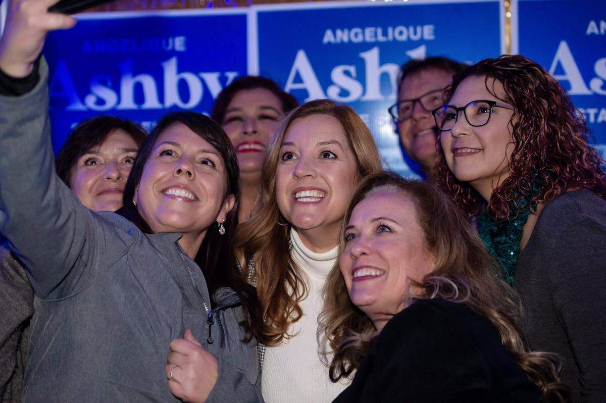 Angelique Ashby poses for a photo with supporters at her state Senate election night party at Bella Bru Cafe in Natomas on Tuesday, Nov. 8, 2022.