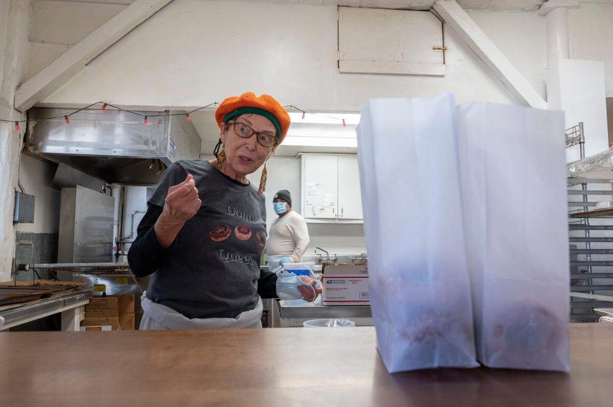 Rainbow Orchards co-owner Christa Campbell, the “Donut Queen,” prepares a bag of her popular sugar-coated apple cider doughnuts on Nov. 17 in Camino.