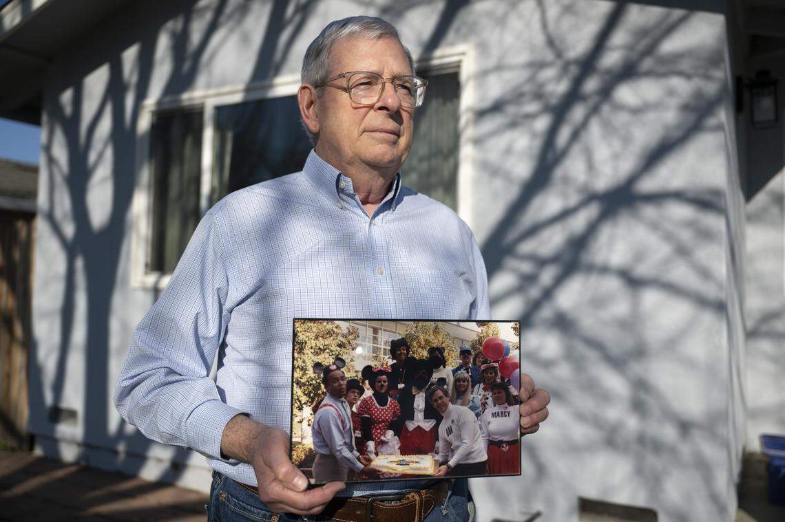 Don Peri, 76, poses for a portrait at his Davis home on Monday as he holds a photograph of himself, his coworkers and Marcy Jacobs at a Disney-themed work party in 1988. Peri says he remembers Jacobs as kind — inquiring about his daughter shortly before she was killed.