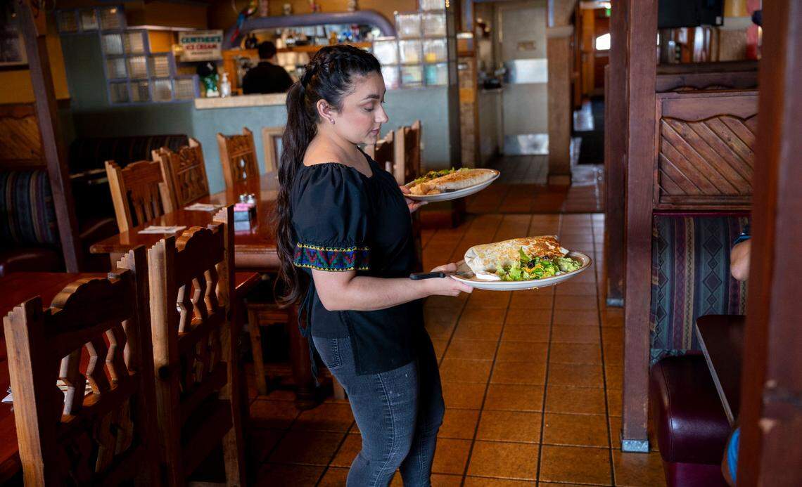Lexi Villalpando serves a table burrito grandes at Caballo Blanco restaurant on Friday.