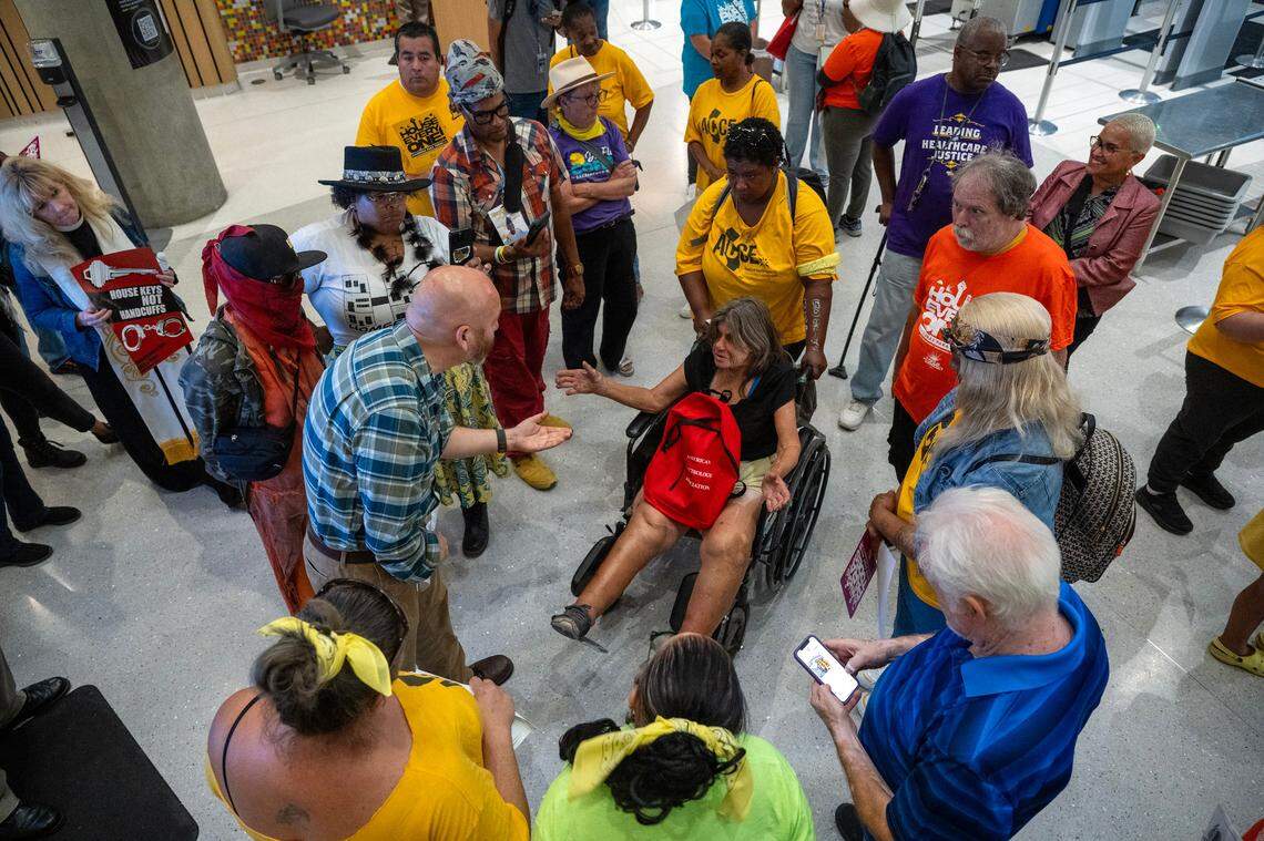 Tena Pflueger, 66, who is homeless and blind in one eye from cancer, describes her situation to Adrian Mata, director of constituent affairs in the governor’s office, during a protest at the Capitol Swing Space on Thursday. “(Gov. Gavin Newsom) lives in a mansion we live in the mud,” she said, explaining that she lives under a bridge with rats and continues to be swept every day.
