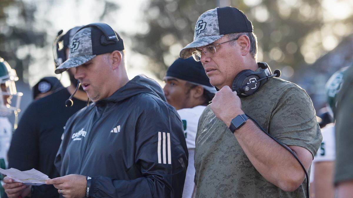 Cal Poly Mustangs head coach Paul Wulff, right, talks with the team on the sidelines during a game at Hornet Stadium on Nov. 11, 2023.