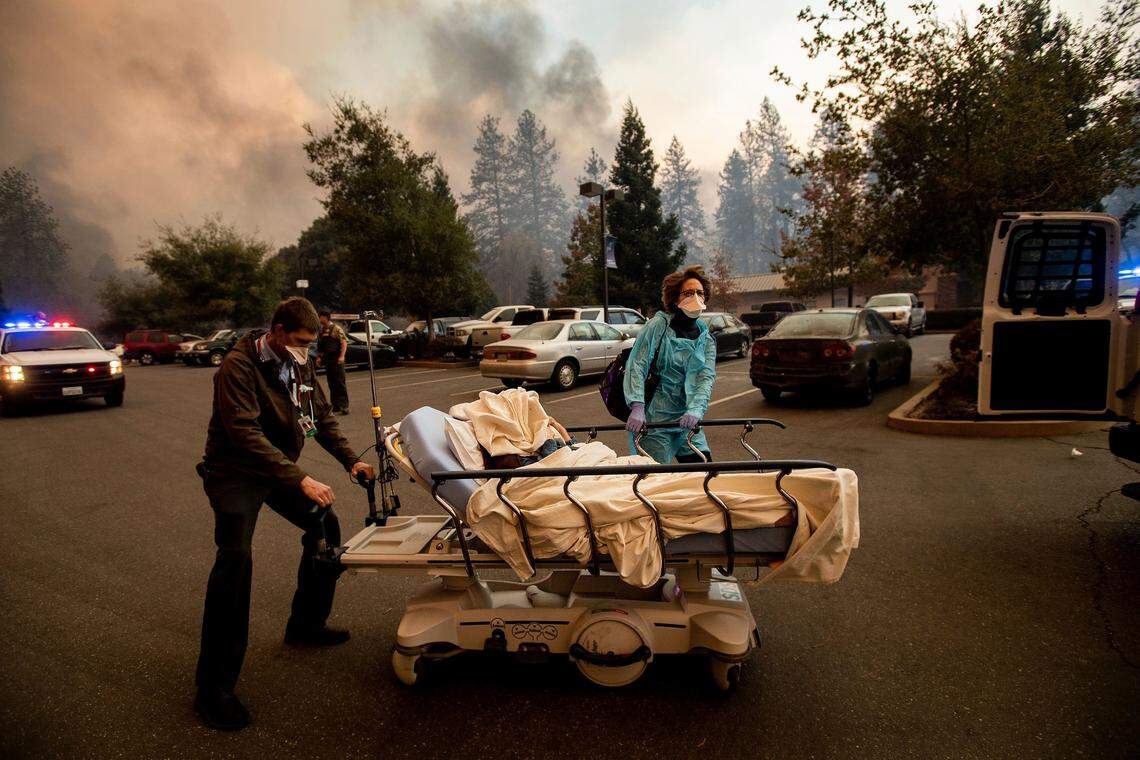 Dr. David Russell and other medical personnel evacuate patients as the Feather River Hospital burns while the Camp Fire rages through Paradise, Calif., on Thursday, Nov. 8, 2018.