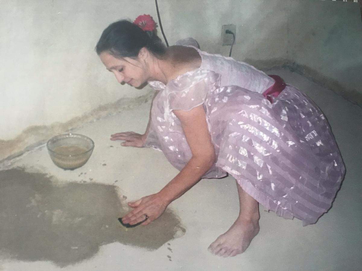 Suzette Nyokka works on the adobe floors of her circular straw-bale home when it was built around 1997.