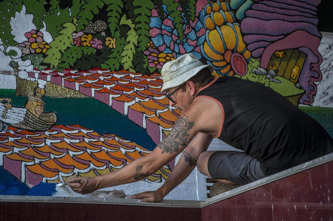 Muralist Shaun Burner works on renovating a piece of the old Tower Records mural on K Street in 2018. Burner received CARES Act funds.