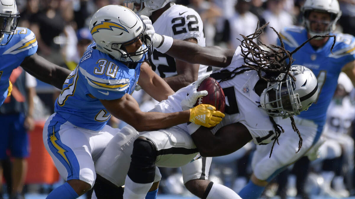 Raiders punt returner Dwayne Harris, right, is hauled down by the Los Angeles Chargers’ Austin Ekeler on Sunday in Carson.