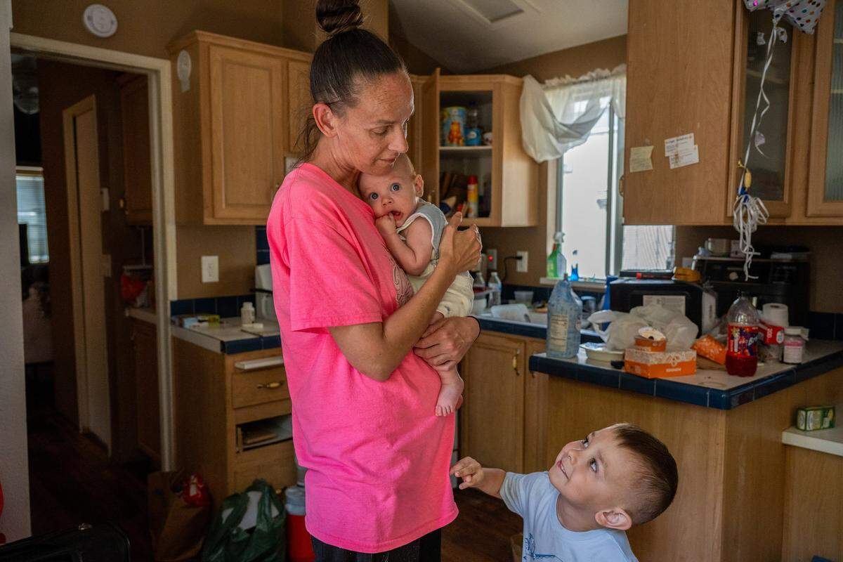 Patricia Miller holds her 4-month-old son, Hayden, as her other son, Hunter, 4, vies for her attention in a city-funded cottage at Arden Acres in Sacramento on Tuesday. Miller said she has no place to go after the city changed the program, leaving families without shelter. She does not own a vehicle.