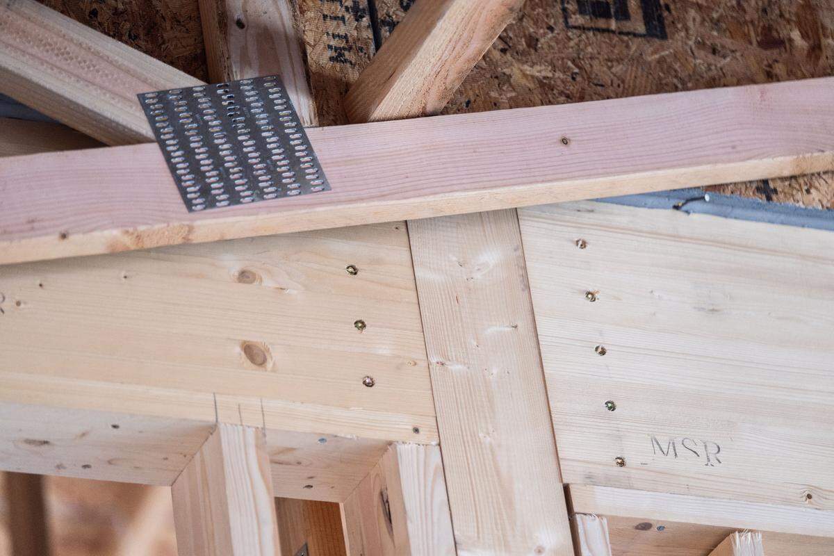 The precision-cut laminated beams and posts, connected with proprietary metal fittings, of the Shawood framing system contrast with roof trusses that employ more traditional American construction techniques in a Folsom model home.