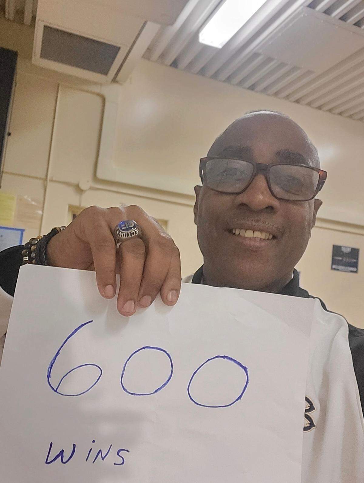 Luther Burbank High School Titans boys basketball coach Lindsey Ferrell holds up a sign celebrating his 600th career win as coach, which he reached Feb. 3 with a win over Fairfield.
