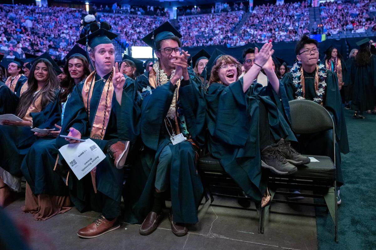 Aaron Kenneth Brown, left, Jackson Huston, center, and Mars Kelsey, right, celebrate as a friend receives a diploma during the 2024 UC Davis commencement ceremony on Friday at Golden 1 Center.