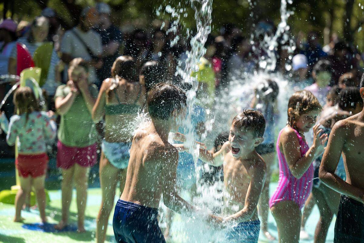Davis residents Troy Yackzan, 7, right, and Teddy Scicoine, 7, play in the water following a ceremony for the opening of Natalie’s Corner Splash Pad in Davis' Central Park on Saturday. The interactive water feature honors Natalie Corona, the Davis police officer killed in the line of duty in 2019.