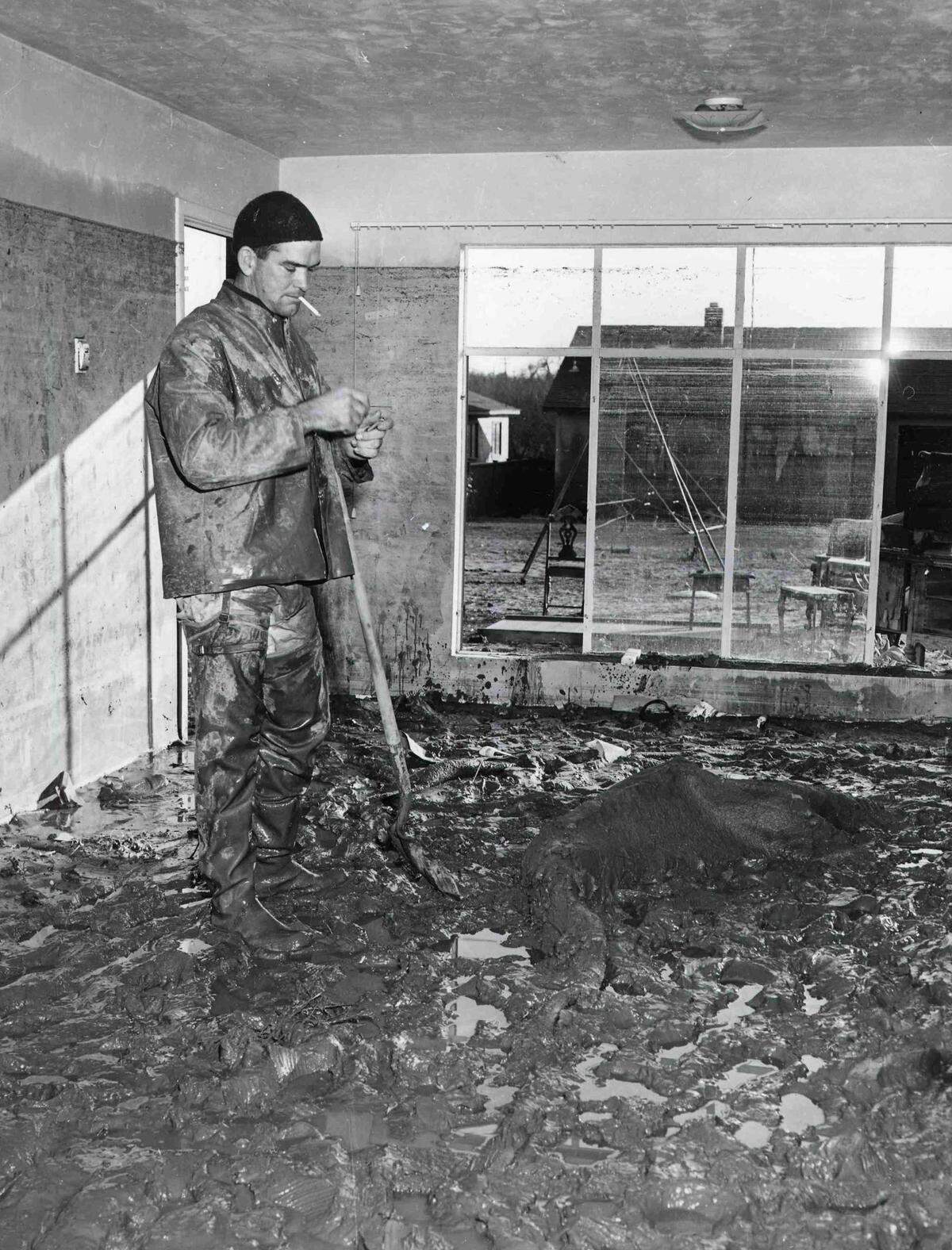Frank Mallory of Park Avenue in flood-soaked Yuba City pauses for a smoke as he works to remove four inches of mud deposited on Dec. 24, 1955, by flood waters in the interior of his home. "We were shocked at what we saw," said Mallory, a PG&E employee. 