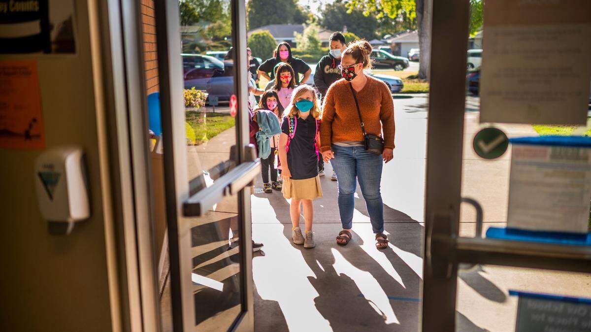 Julia Johnson is brought into school by her mother, Jenny Johnson, at Caroline Wenzel Elementary in Sacramento on Thursday, April 8, 2021. The Sacramento City Unified School District will require eligible students and staff to be vaccinated by Nov. 30.