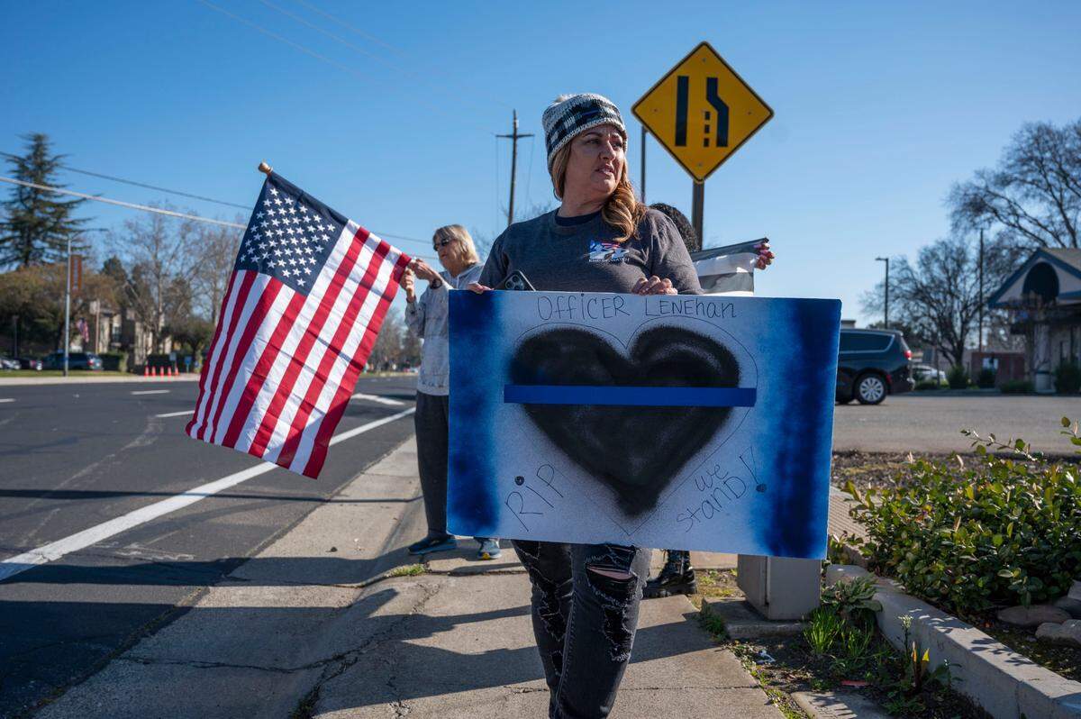 Brandy Velasco, of Elk Grove holds a sign on Elk Grove Boulevard as she and others wait for a procession for fallen Elk Grove police officer Tyler Lenehan on Tuesday, Jan. 25, 2022. “It’s devastating. My heart is just broken,” said Velasco who’s son is a police officer in San Diego. Lenehan died after he collided with a wrong way driver on his way to work early Friday morning in Sacramento on Jan. 21.