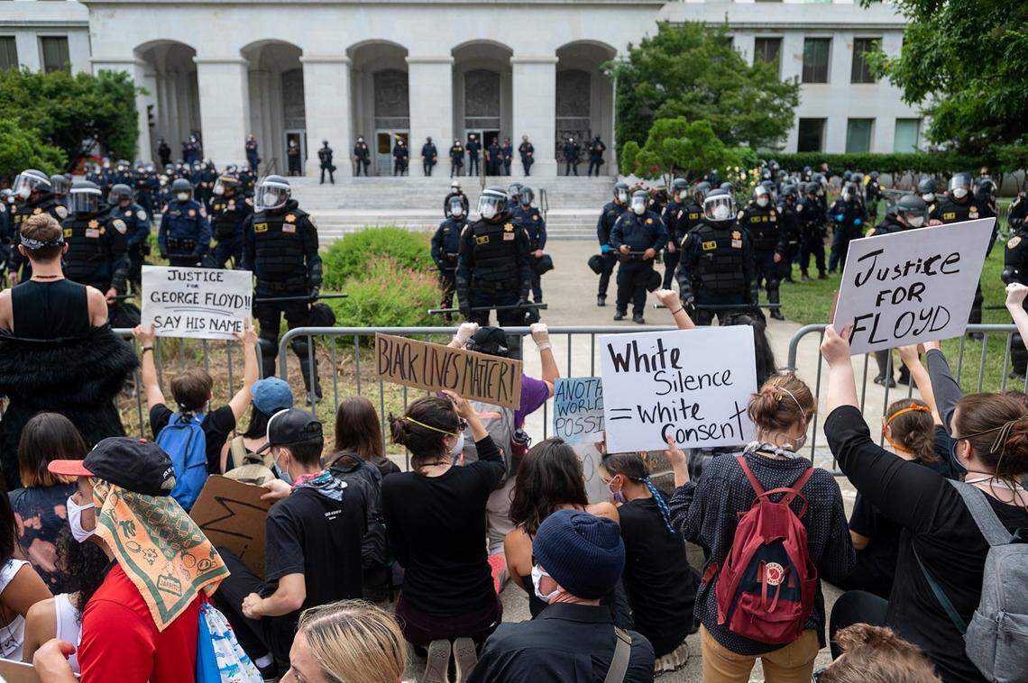 Demonstrators kneel at fence as California Highway Patrol officers guard the state Capitol on Sunday, May 31, 2020, during a protest over the death of George Floyd. Floyd died in Minneapolis Monday after being detained by police.