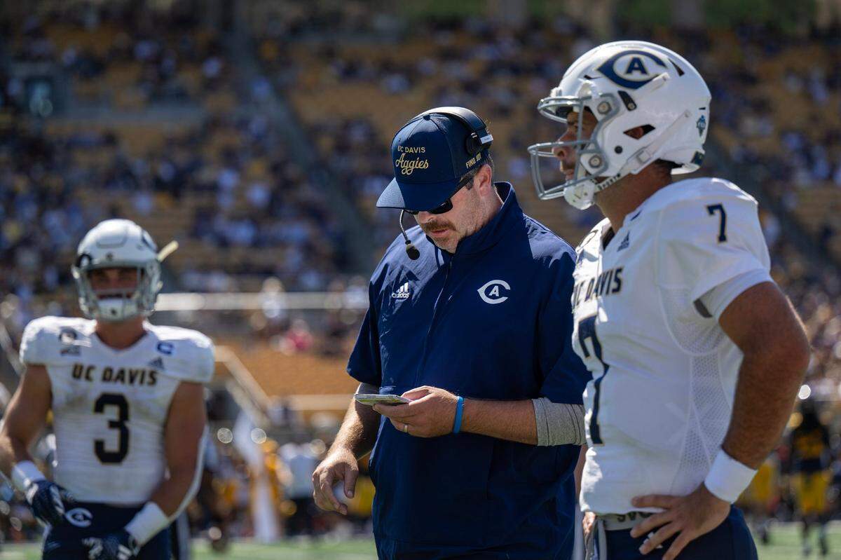 UC Davis Aggies head coach Tim Plough talks with Aggies quarterback Miles Hastings (7) during a game against the California Golden Bears on Saturday at Memorial Stadium in Berkeley.