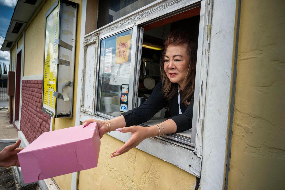 Suzie Hem, owner of Baker’s Donuts on Florin Road in Sacramento, hands an order of her doughnuts to a driver in 2022.