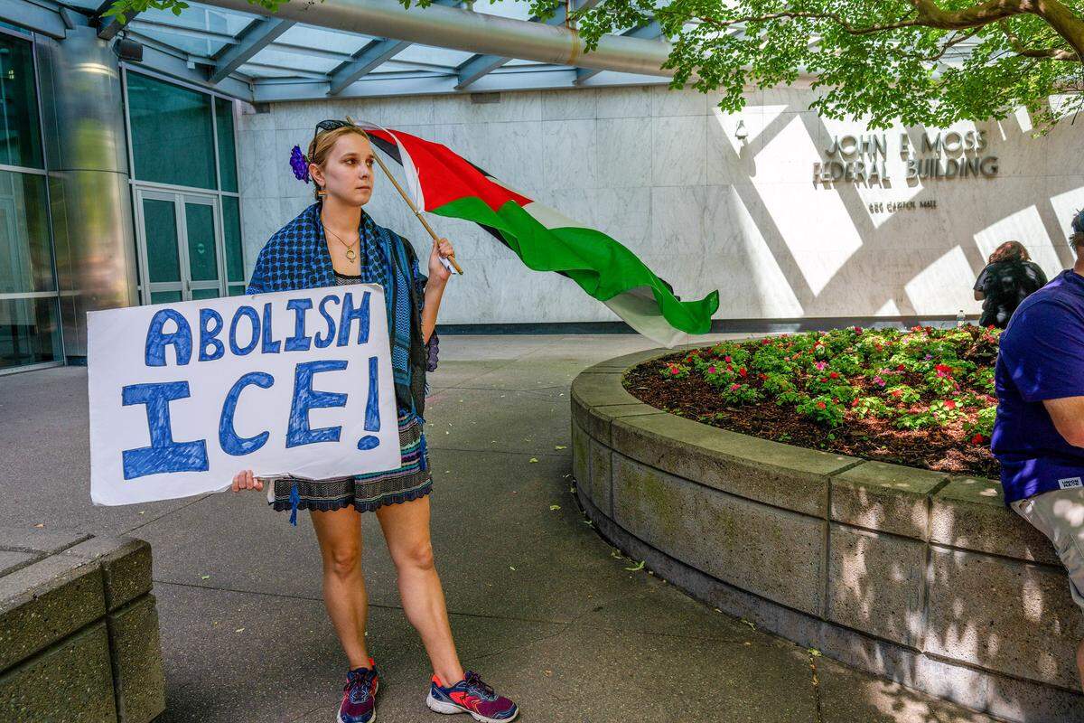 Samantha, of Sacramento, holds a sign and waves a flag outside the John E. Moss Federal Building in Sacramento on Friday. She joined with hundreds in a "Day Without Immigrants" anniversary march, calling on ICE to leave Sacramento.