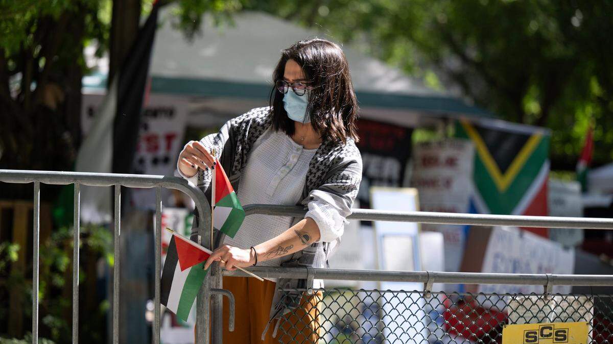 A pro-Palestinian activist inserts small Palestinian flags on Wednesday, May 1, 2024, into fence openings outside of the tented area the demonstrators took over three days ago at Sacramento State to protest the war in Gaza. Protesters are asking the university to divest from investments in Israel.