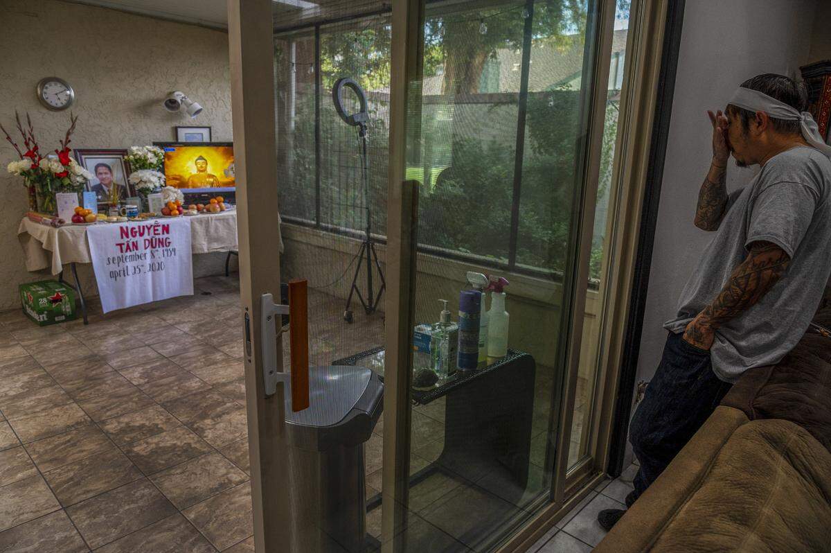 Bao Nguyen, 45, says “I think the whole community would be here,” as he waits for visitors to pay respects in his home, on Monday, May 4, 2020, where he and his wife Trang Nguyen created a prayer room to honor his father Dung Tan Nguyen who died on April 25. If it wasn’t for the coronavirus, at least 15 Buddhist monks would’ve chanted prayers for him, but instead a video of chanting is played. Also in the room is an array of hand sanitizer, gloves, masks and cleaning fluids for those to use during their visit. “It’s kind of a sad way to do it. I’m not used to it. It’s kind of the new way, new normal of our world right now,” said Nguyen who was explaining that only four people will be allowed at the funeral service and that only two people at a time will be allowed to lay flowers on the casket after it is lowered into the grave at the cemetery.