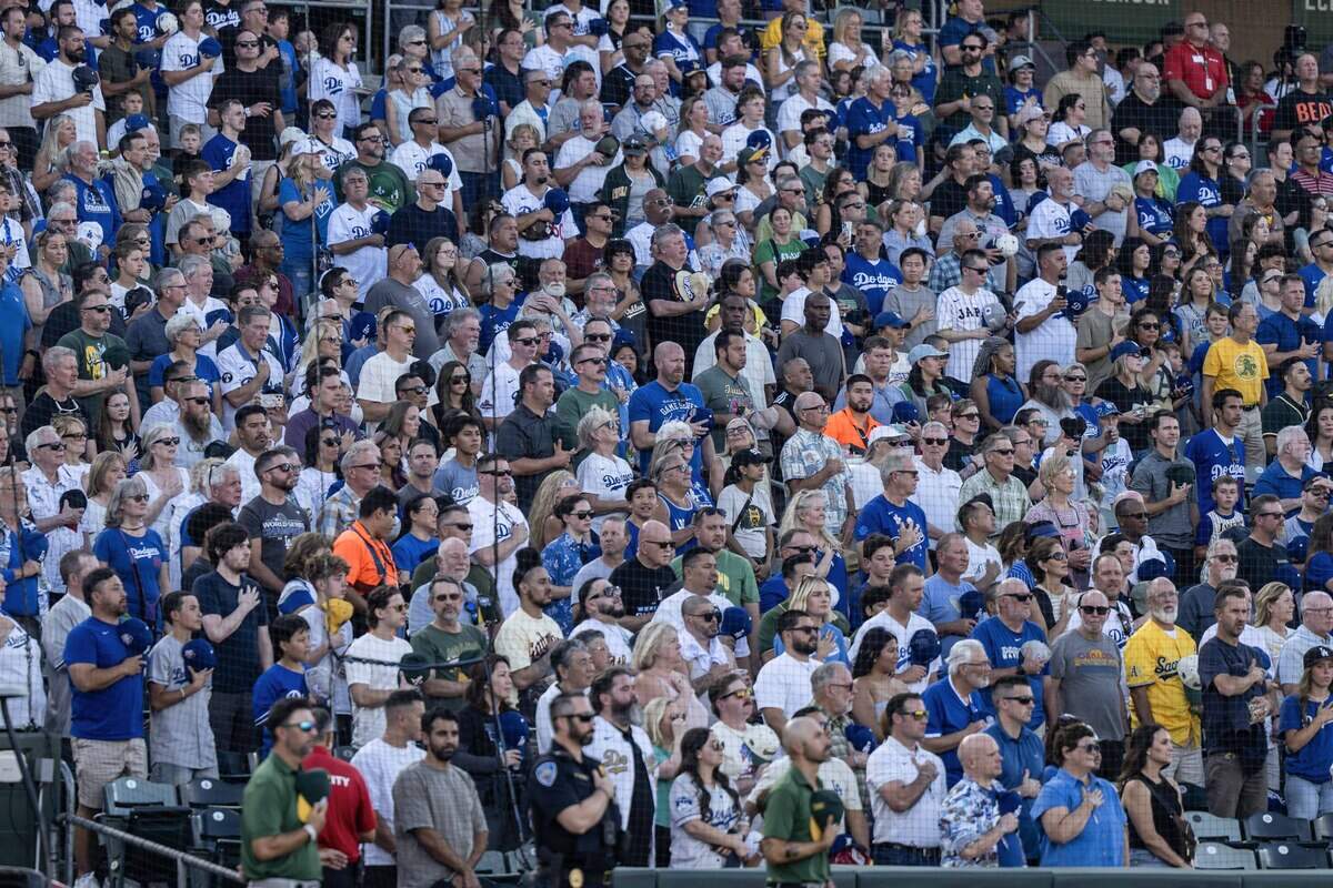 Fans, wearing mostly blue, stand for the national anthem at Sutter Health Park in West Sacramento before a game between the Athletics and the Los Angeles Dodgers on Monday, June 29, 2026.