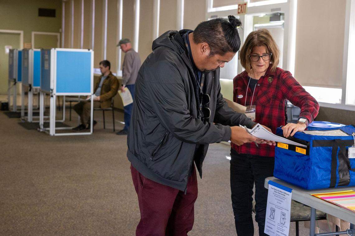 Election officer Susan Dlugach helps Justin Garon cast his vote with a paper ballot at the Sierra 2 vote center in Sacramento’s Curtis Park neighborhood on Monday, Nov. 4, 2024.