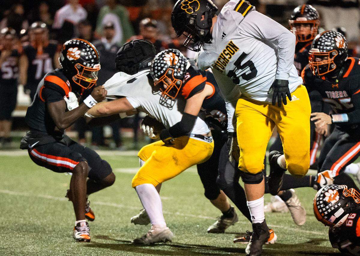 Roseville Tigers strong safety Harold Neufville Jr. (9) and outside linebacker Cash Fischer (15) stop Hughson Huskies running back Eli Wilbanks (21) for no gain in the second half of a CIF Sac-Joaquin Section Division IV semifinal in Roseville on Friday, Nov. 21, 2025. 