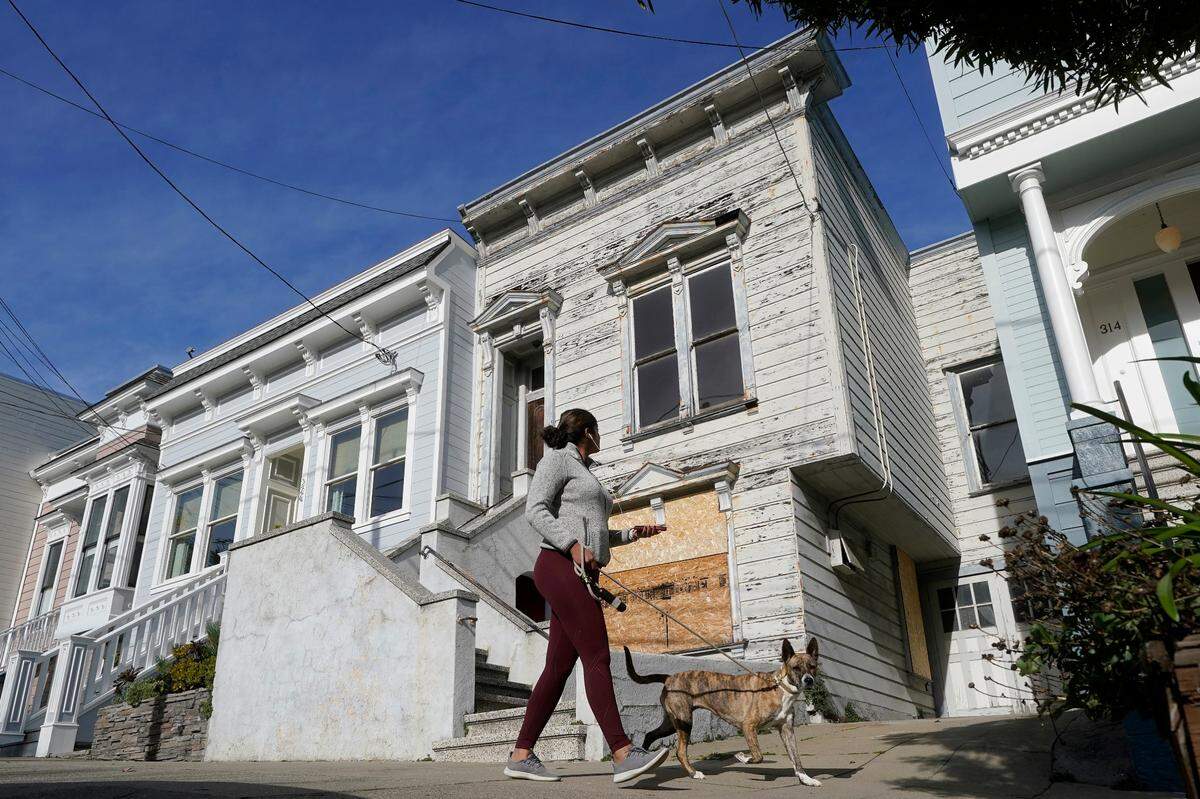 A pedestrian walks a dog past a recently sold Victorian home in San Francisco, in January. The decaying, 122-year-old Victorian marketed as “the worst house on the best block” of San Francisco recently sold for nearly $2 million — an eye-catching price that the realtor said was the outcome of overbidding in an auction.