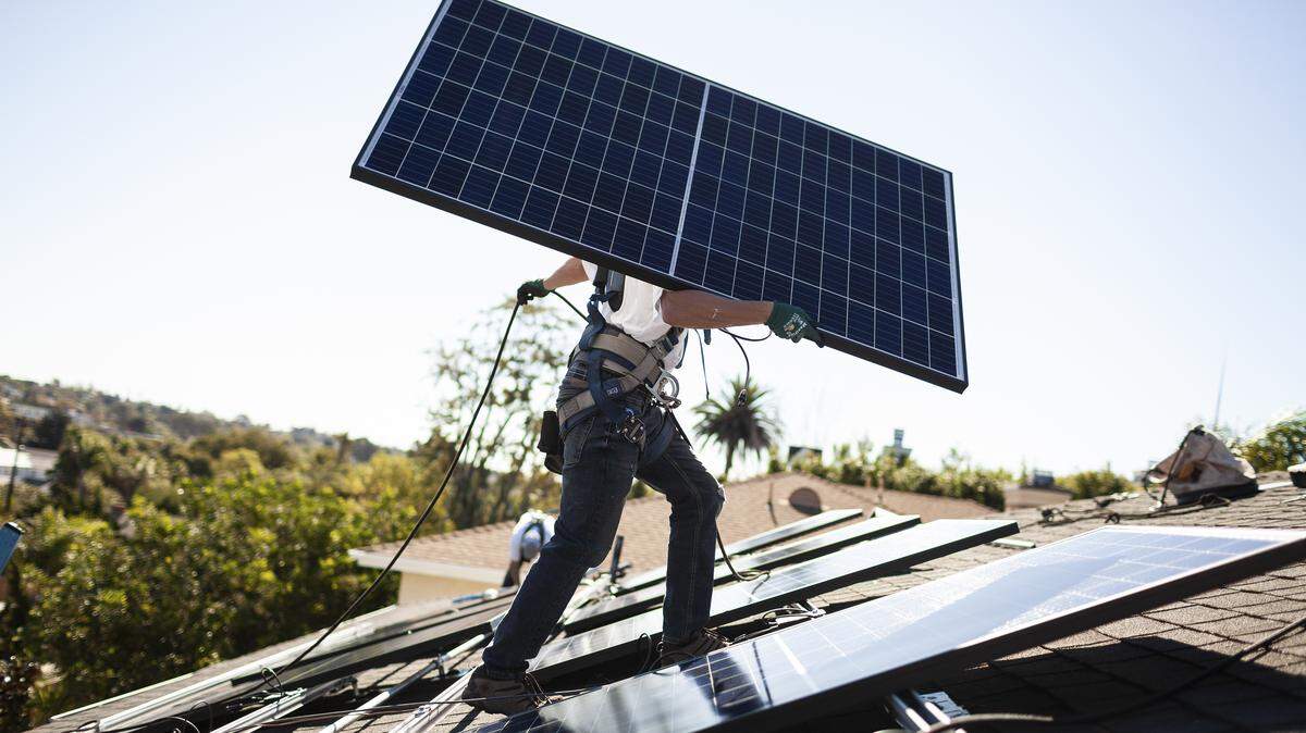 A worker carries a solar panel into place at a customer’s home in Carlsbad, Calif., Oct. 18, 2018.