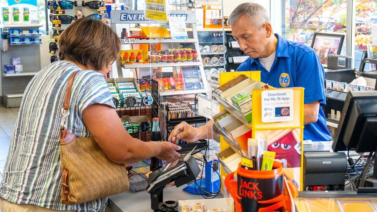 A 76 Gas Station attendant sells a Mega Millions lottery ticket to a customer on Tuesday, August 1, 2023.