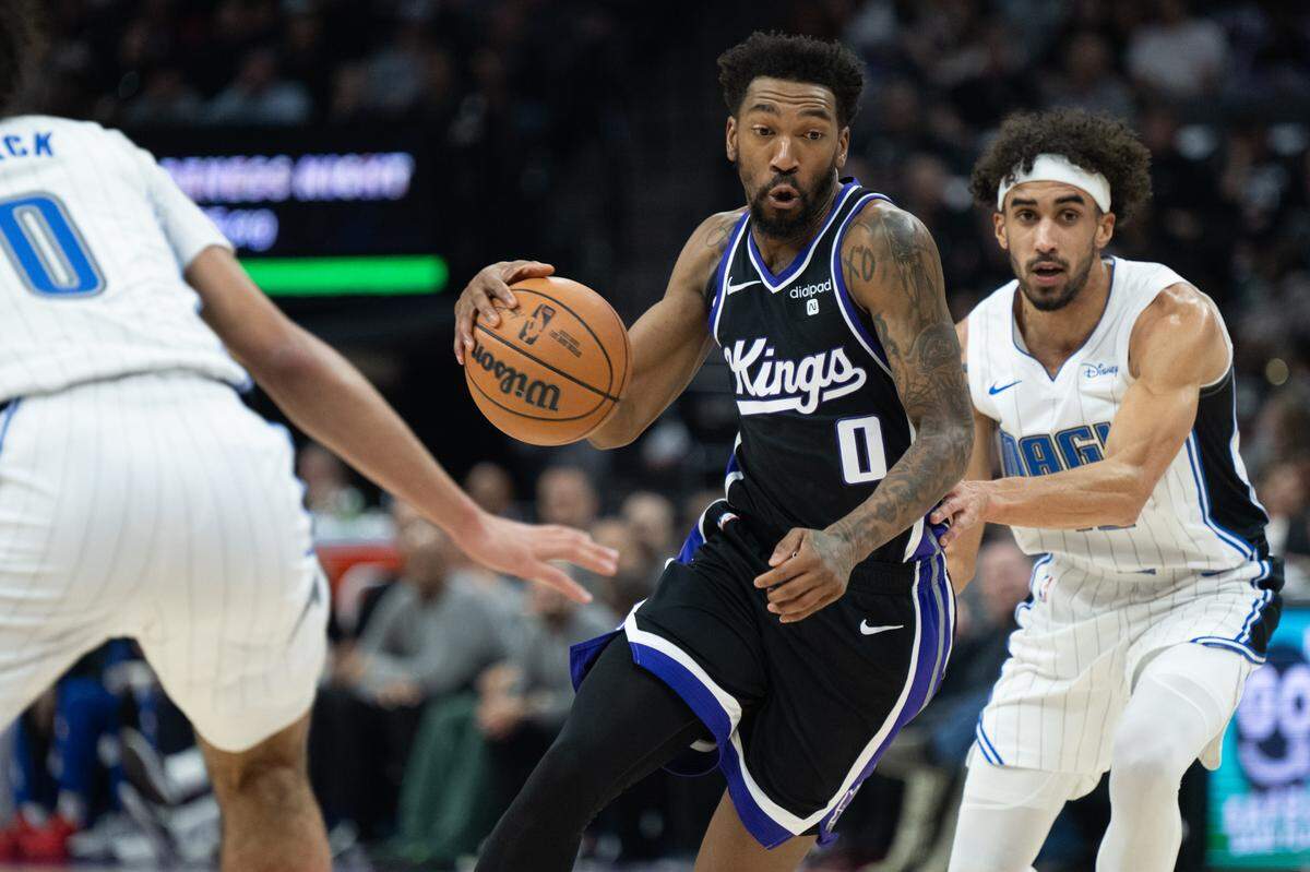 Sacramento Kings guard Malik Monk (0) drives between Orlando Magic guard Anthony Black (0) and guard Trevelin Queen (12) during an NBA game at Golden 1 Center on Wednesday, Jan. 3, 2024.