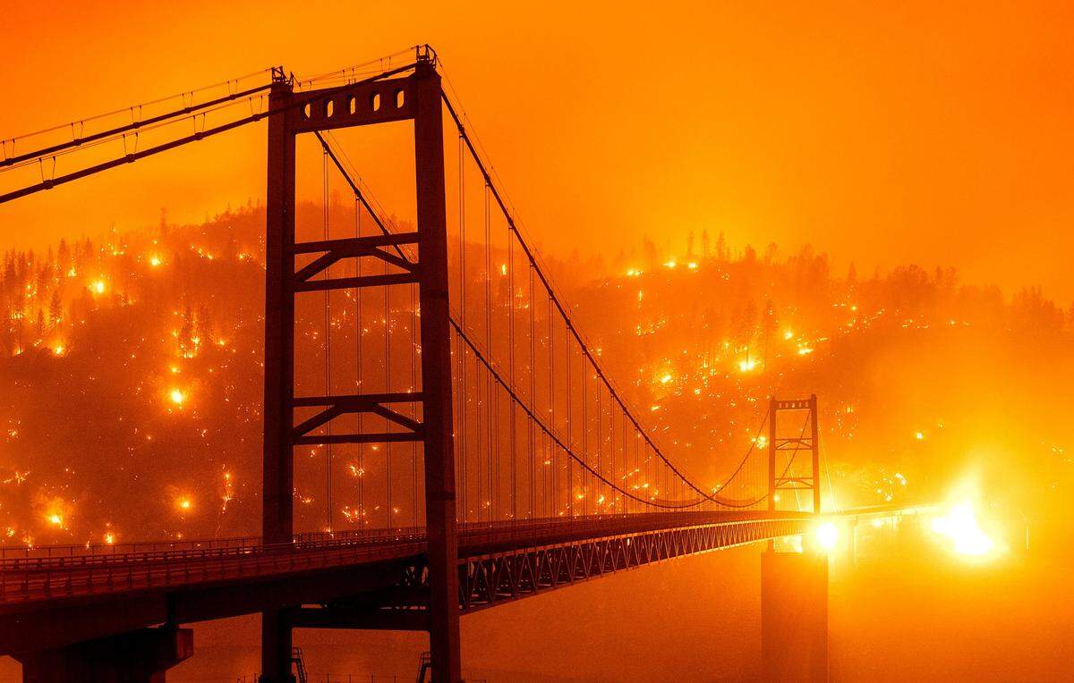 In this image taken with a slow shutter speed, embers light up a hillside behind the Bidwell Bar Bridge as the Bear Fire burns near Oroville on Wednesday, Sept. 9, 2020. The blaze, part of the lightning-sparked North Complex, expanded at a critical rate of spread as winds buffeted the region.