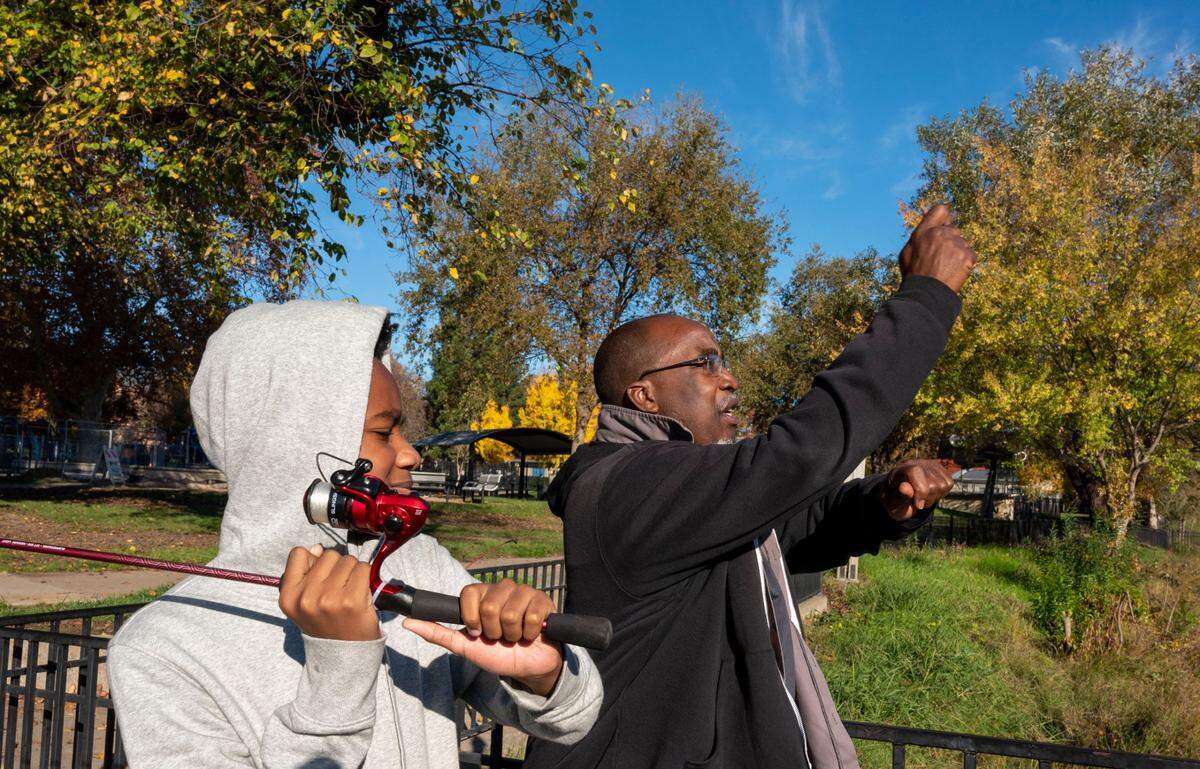 Timothy Poole, founder of Hooked on Fishing not on Violence, shows Brandon Clay Jr., 14, how to cast a line while fishing at Southside Park in November. Poole’s criminal record – erased in 2019 through an expungement process with Legal Services of Northern California – could have barred him from working with children in schools.