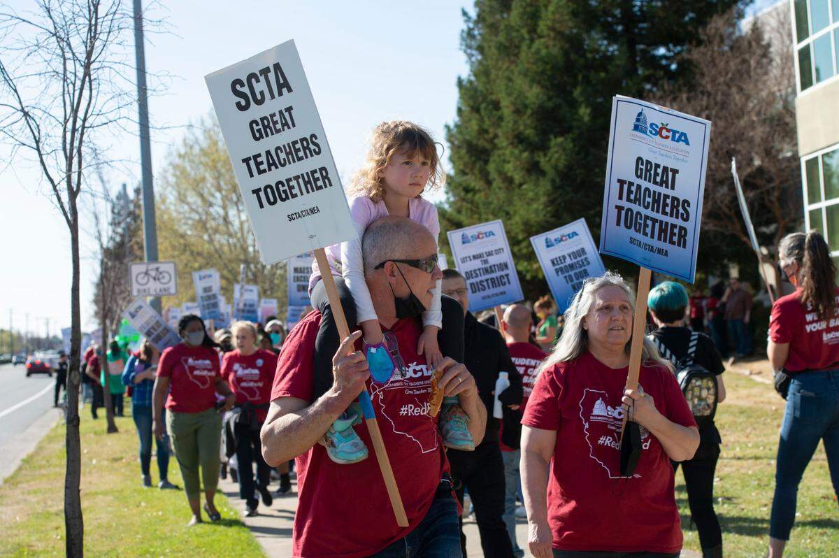 Middle school special education teacher Joseph Puentes, left, carries his daughter Olivia, 5, on his shoulders as members of the Sacramento City Teachers Association rally at the Serna Center on Thursday. They said they will strike next Wednesday if they can’t come to an agreement in good faith with the Sacramento City Unified School District.