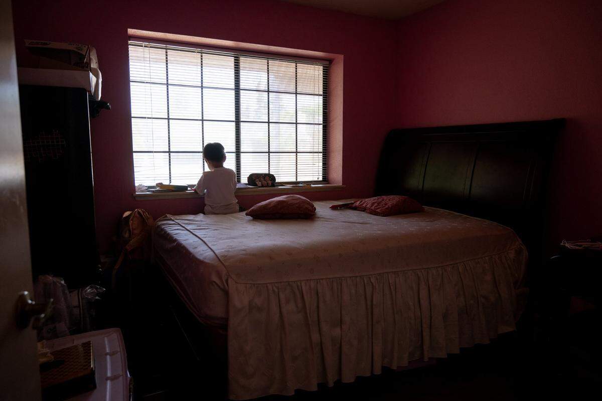 Johnny Nguyen, 5, sits alone in July on a bed in the home of grandmother Phuong Hoang, 80, who is caring for her two young grandchildren after the death of their parents in May. He doesn’t quite fully understand that they are gone, she said.