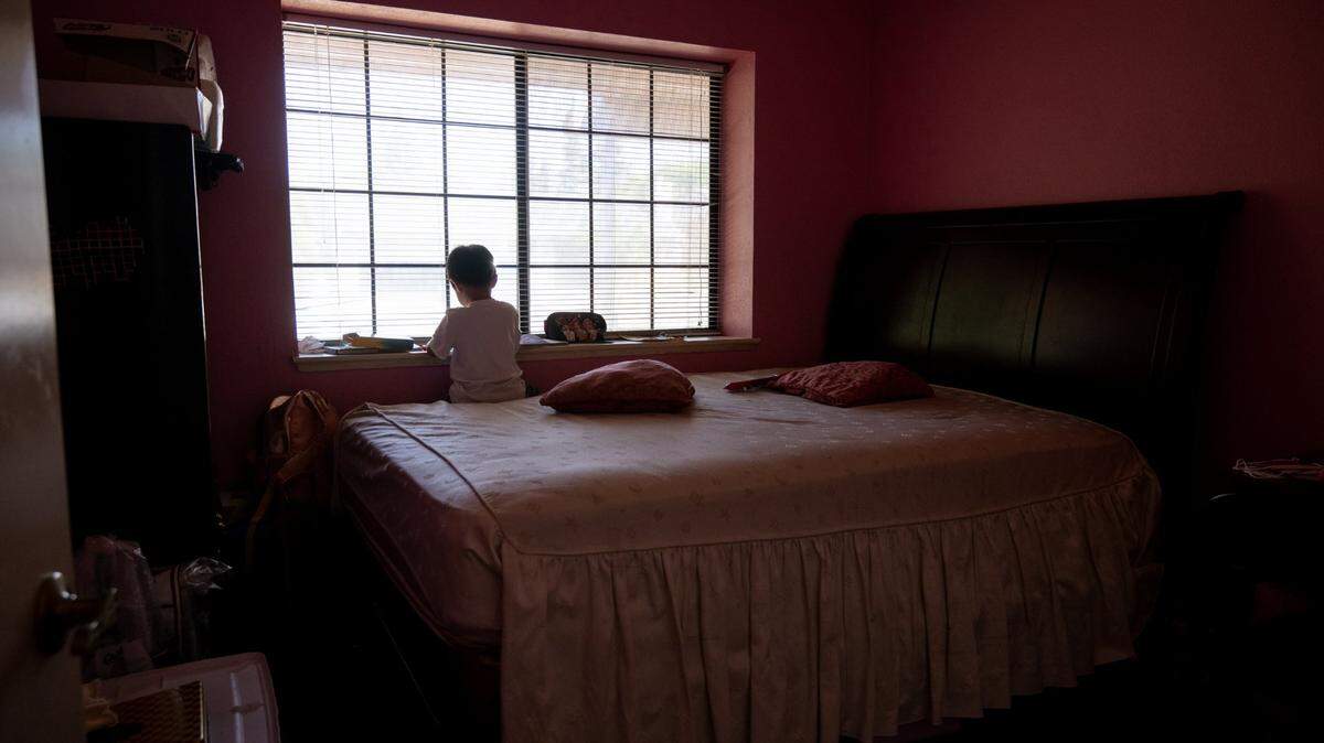 Johnny Nguyen, 5, sits alone on a bed on July 25, 2022, in the home of grandmother Phuong Hoang, 80, who is caring for her two young grandchildren after the death of their parents in May. He doesn’t quite fully understand that they are gone, she said.