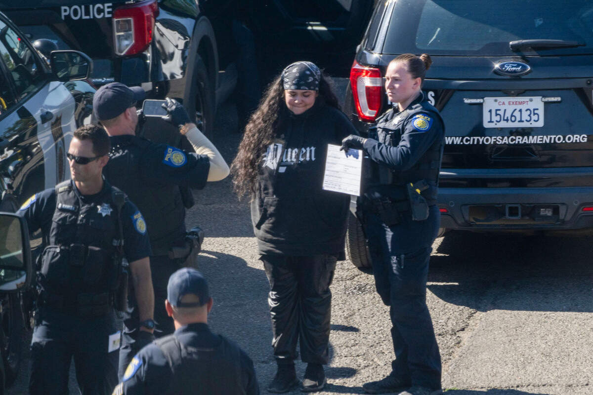 A Sacramento police officer detains a person at Camp Resolution on Monday. The deadline for a group of homeless people to vacate the encampment on a city-owned lot passed overnight.